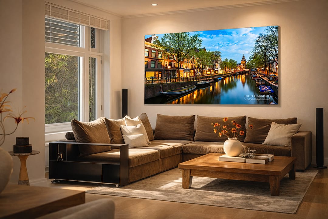 Large-scale fine art residential installation featuring Amsterdam canal wall art on HD acrylic, capturing the Spiegelgracht at blue hour with glowing streetlights, historic canal houses, calm water reflections, and the illuminated Rijksmuseum tower above a modern sofa.