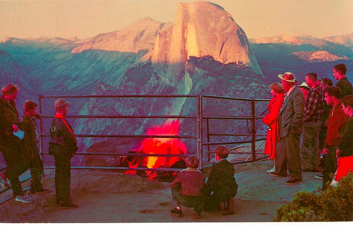 people standing around a burning fire with glowing embers on Glacier Point overlooking Half Dome before pushing them off to create the man made Yosemite Firefall in 1950