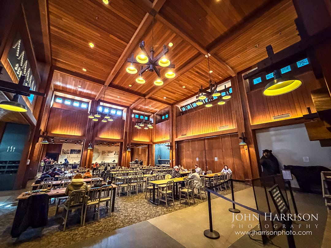 Interior of the Curry Village Dining Pavilion cafeteria in Yosemite Valley with rustic wood beams and dining tables inside Yosemite National Park.