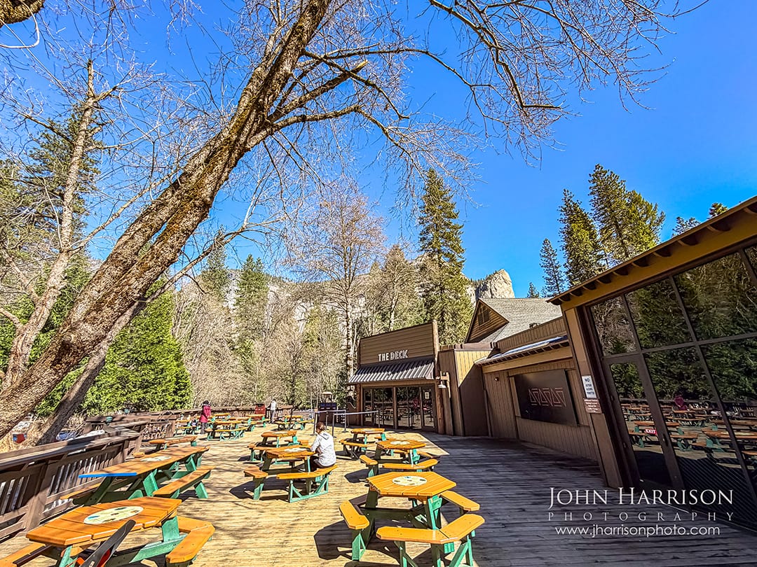 Outdoor seating area at the Curry Village Pizza Deck in Yosemite Valley with picnic tables and forest views in Yosemite National Park.