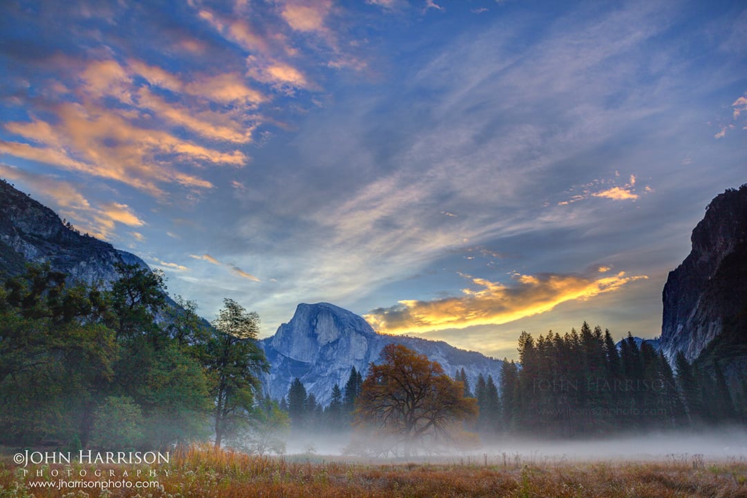 Yosemite Valley, Half Dome at sunrise with autumn meadow fog and silhouetted elm trees in Yosemite National Park, California.
