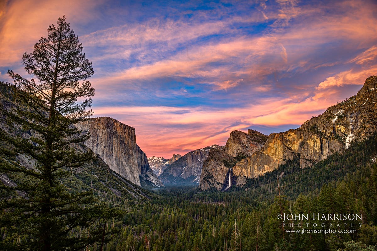 Colorful spring sunset from Tunnel View in Yosemite National Park with El Capitan, Bridalveil Fall, and Yosemite Valley glowing beneath pastel clouds
